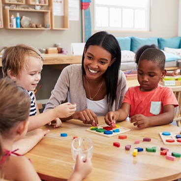 Teacher And Pupils Using Wooden Shapes In Montessori School Teacher And Pupils Using Wooden Shapes In Montessori School